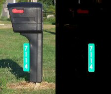 911 Sign, white reflective text on green background that reads 7114. Mounted vertically on black mailbox.